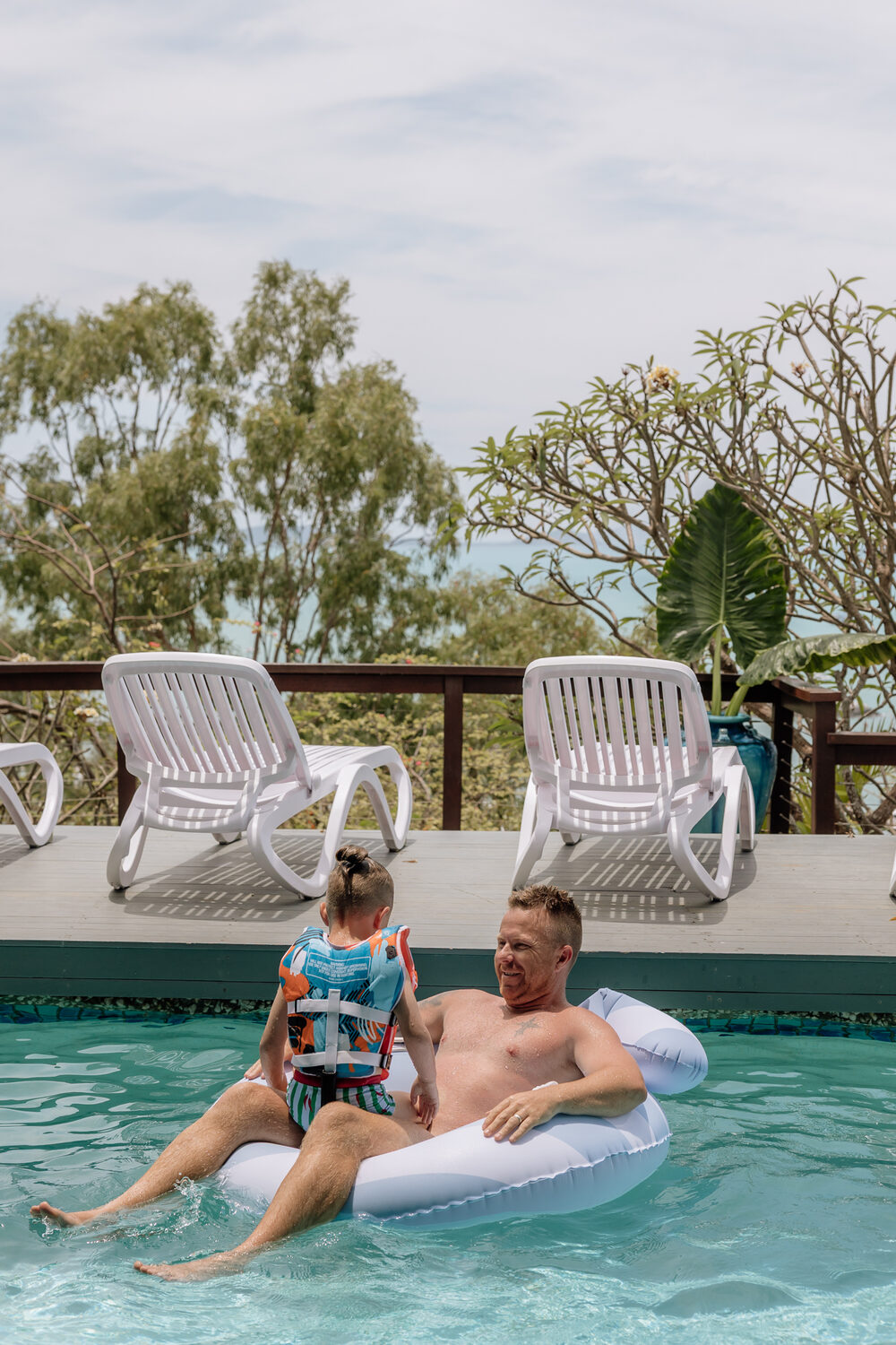 Family relaxing in the pool with sea views behind