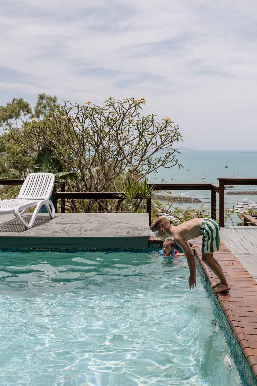 Kids diving into the pool with the marina beyond