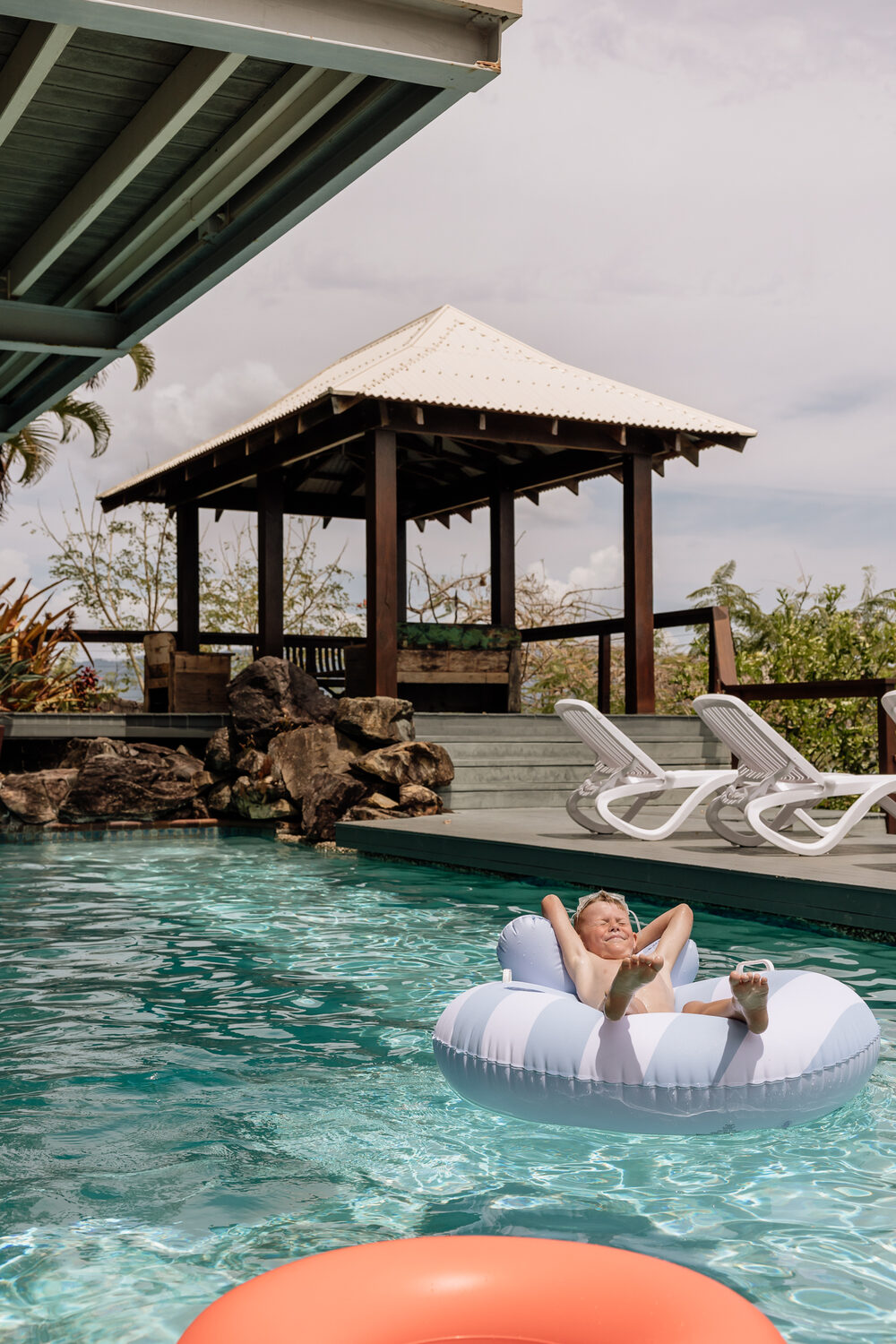 Dad and toddler floating in the pool with the Coral Sea behind